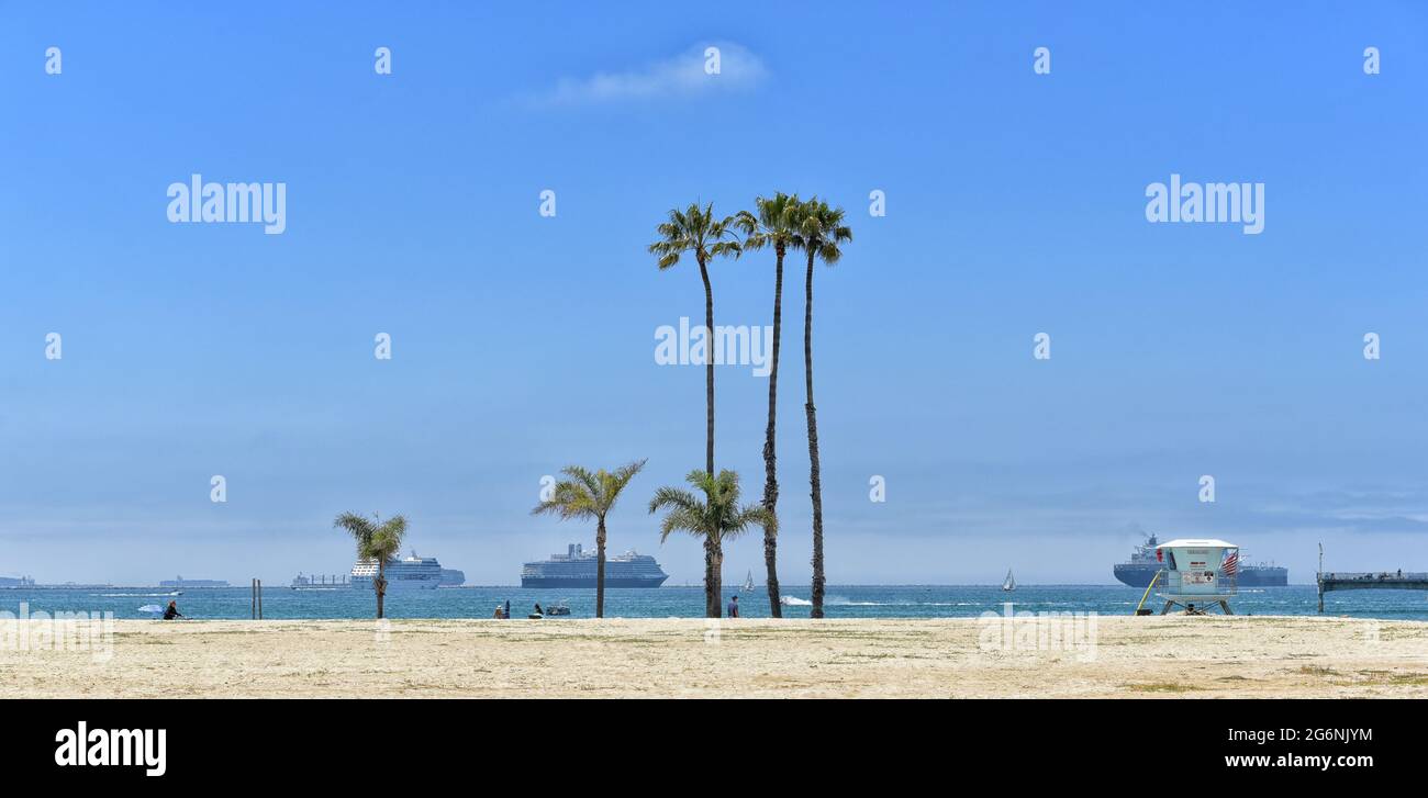 LONG BEACH, CALIFORNIA - 5 JULY 2021: Belmont Shore Beach with Crusie Ships, Sail Boats and people on the sand. Stock Photo