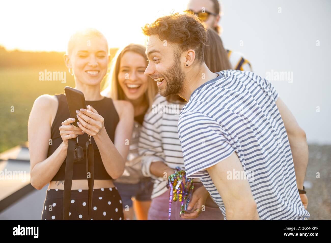 Young friends hang out at rooftop terrace on sunset Stock Photo