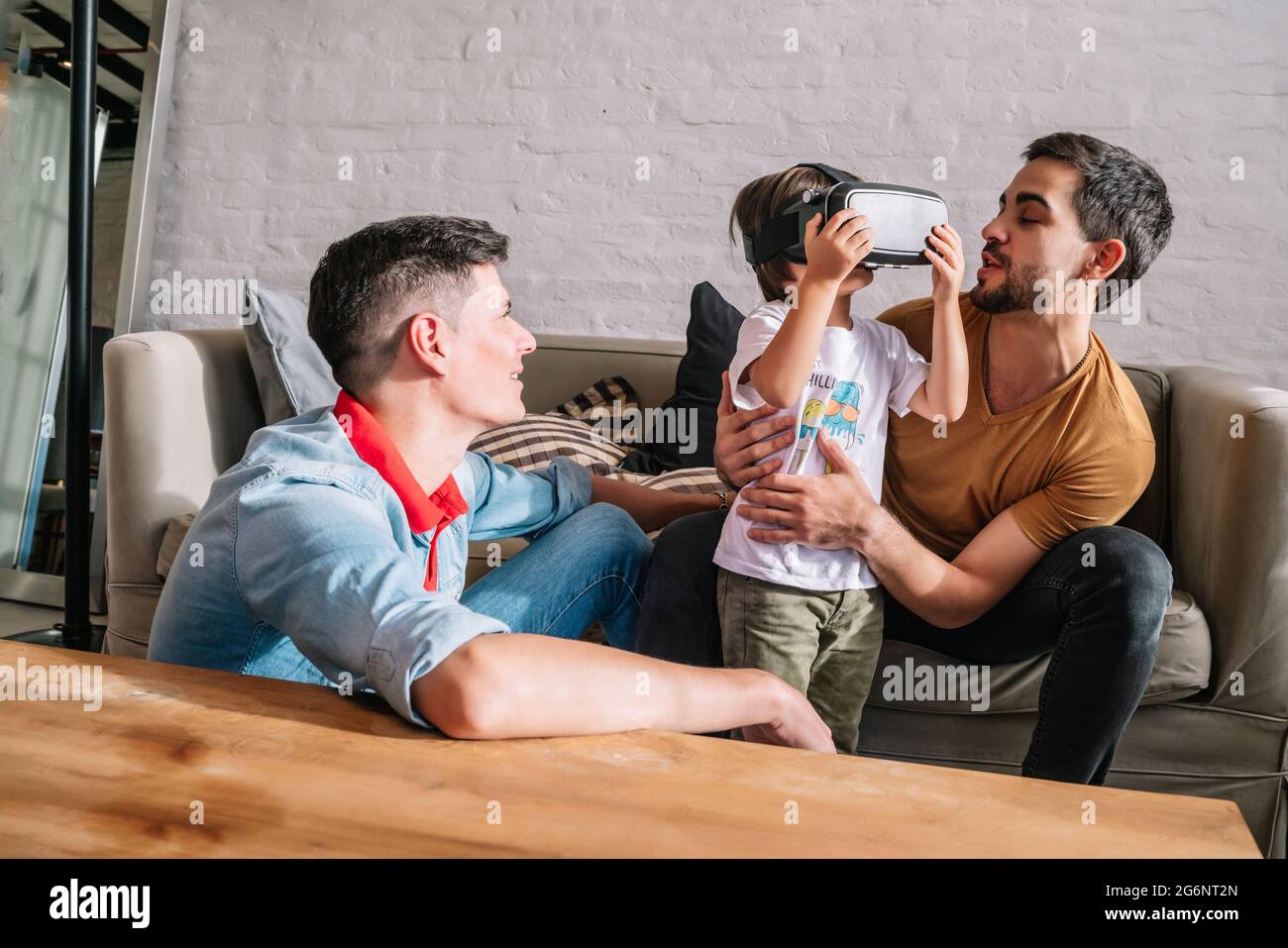 Gay couple and their kids playing video games with VR glasses Stock Photo -  Alamy