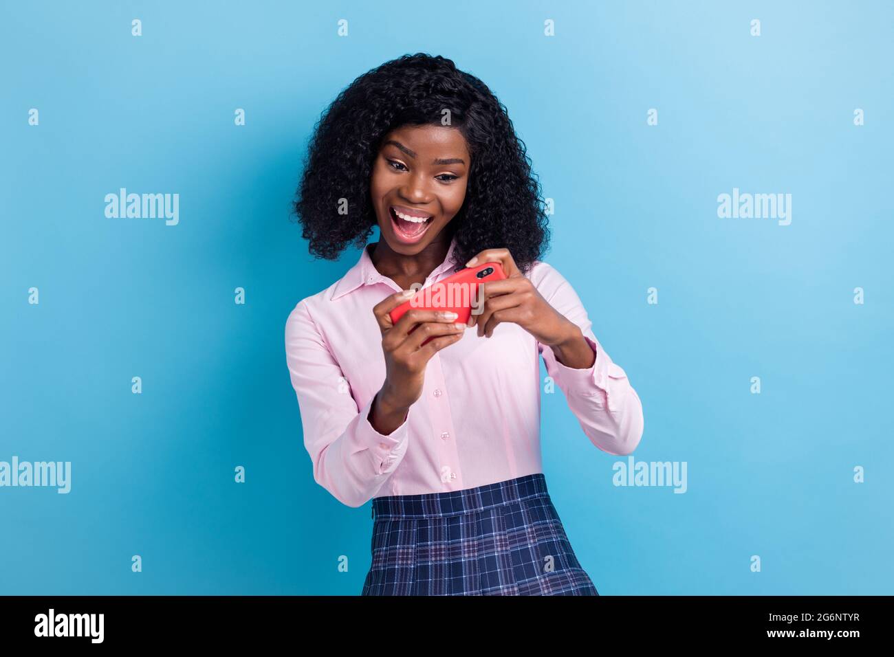 Photo of young excited afro girl happy positive smile play game cellphone isolated over blue color background Stock Photo