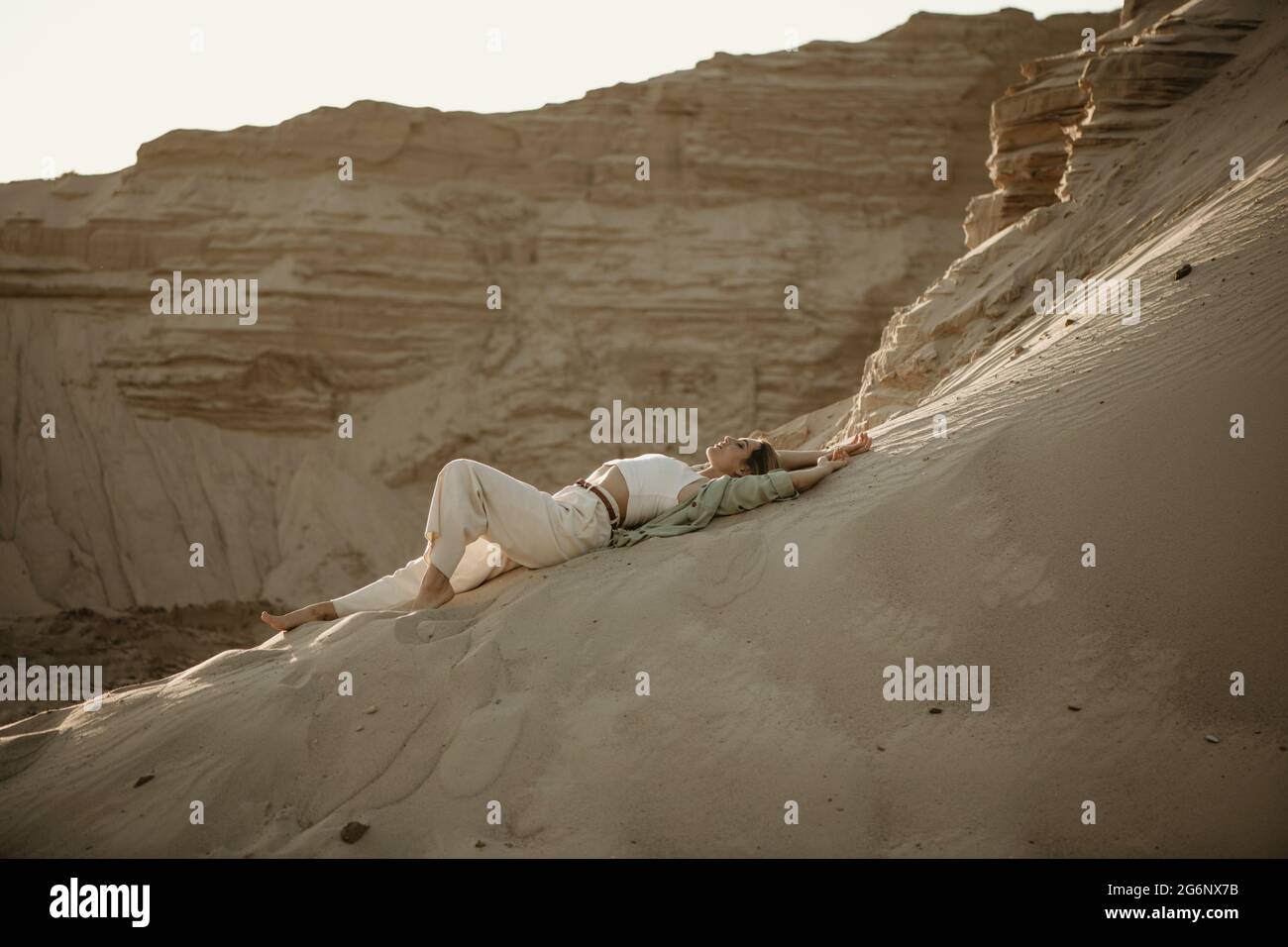 Young stylish woman lying on sand in desert Stock Photo - Alamy