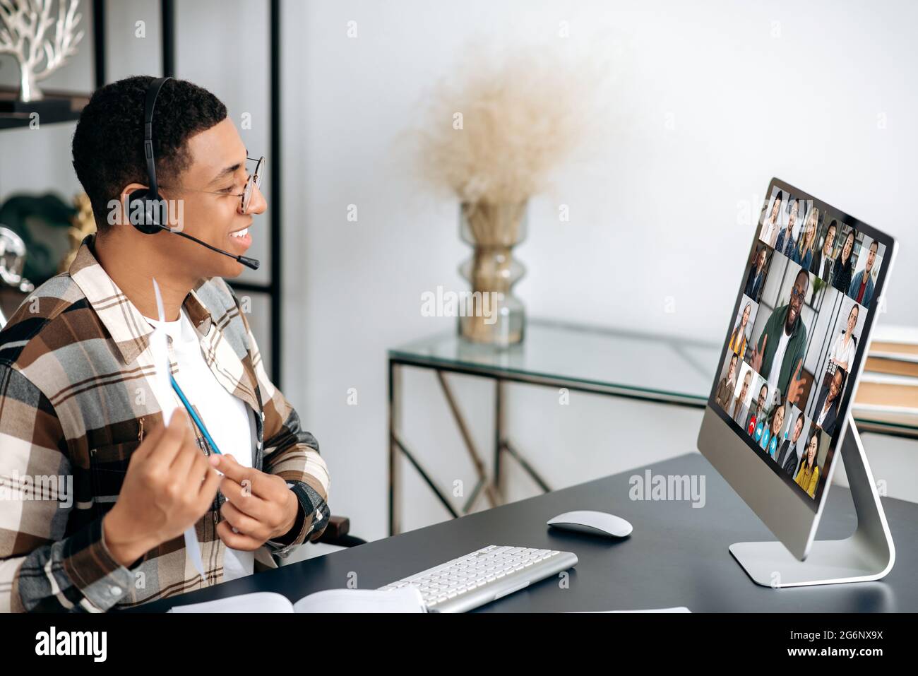 Distant video communication. Latino young man, employee or ceo, communicates via video conference with business team, discusses a project, analyzes a business plan, having online group brainstorm Stock Photo