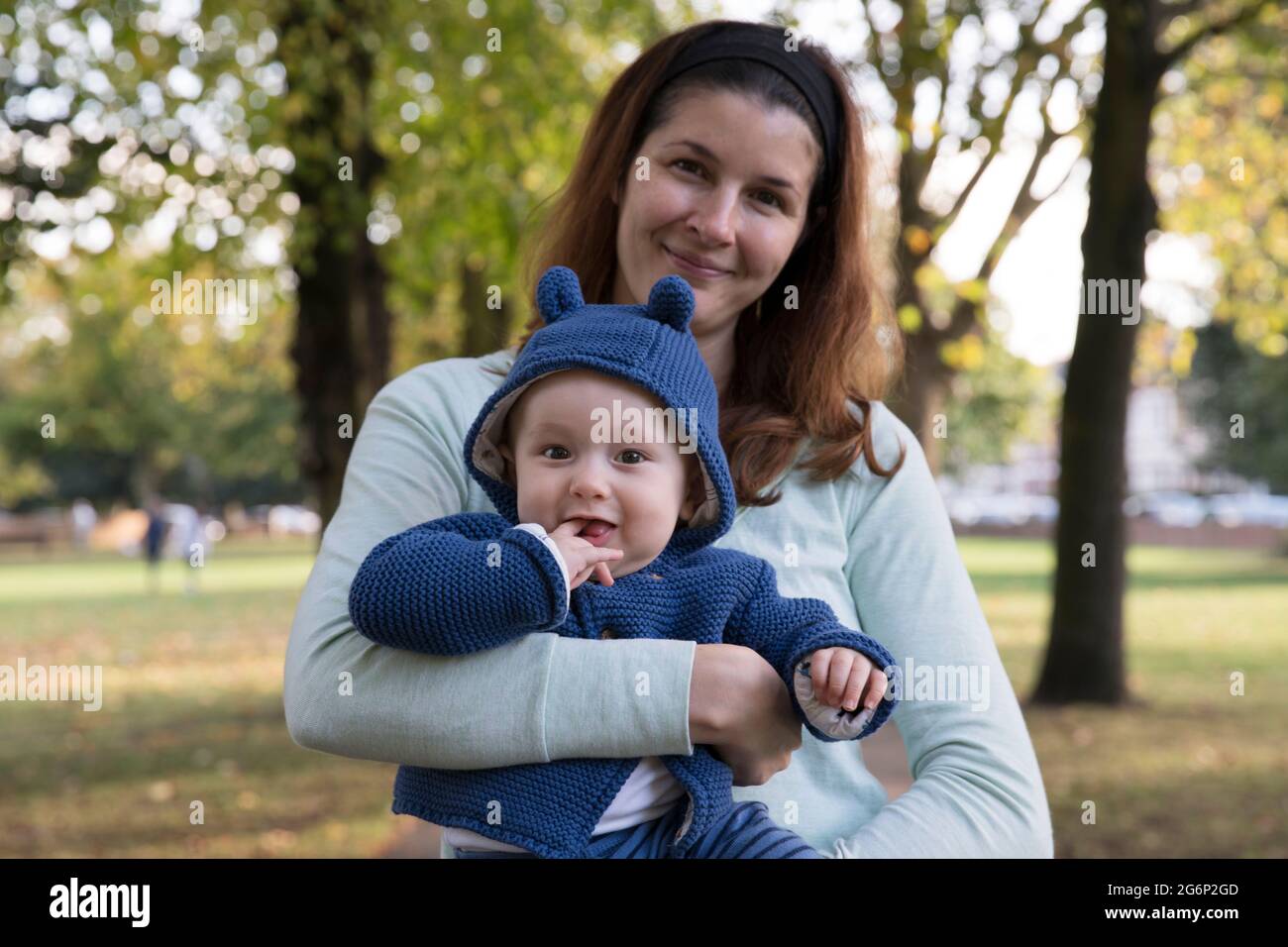 A woman holding her baby in a park Stock Photo