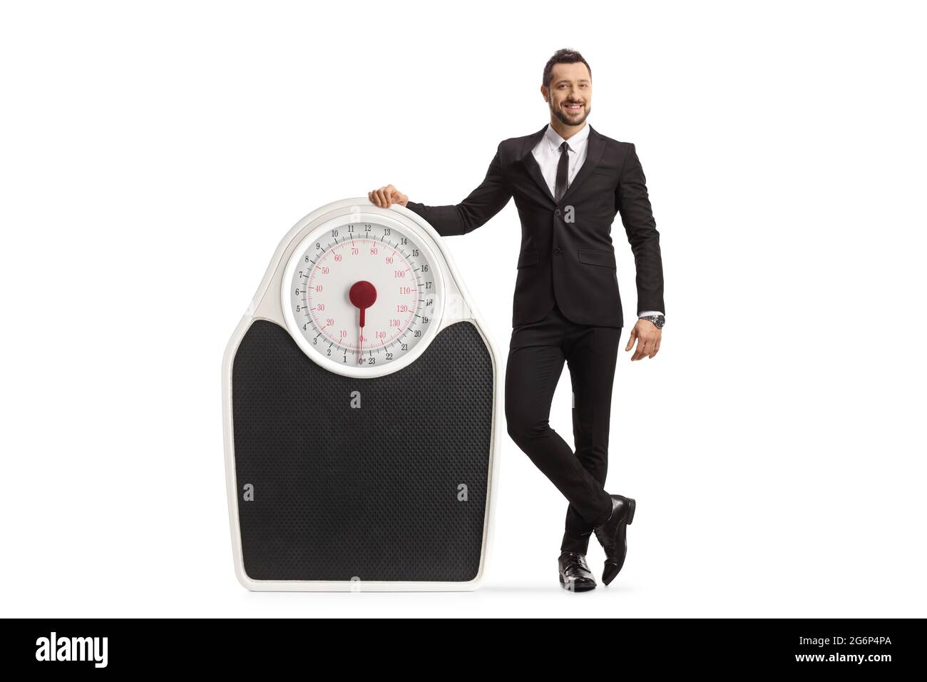 Full length portrait of a man in a suit and tie leaning on a big weight ...