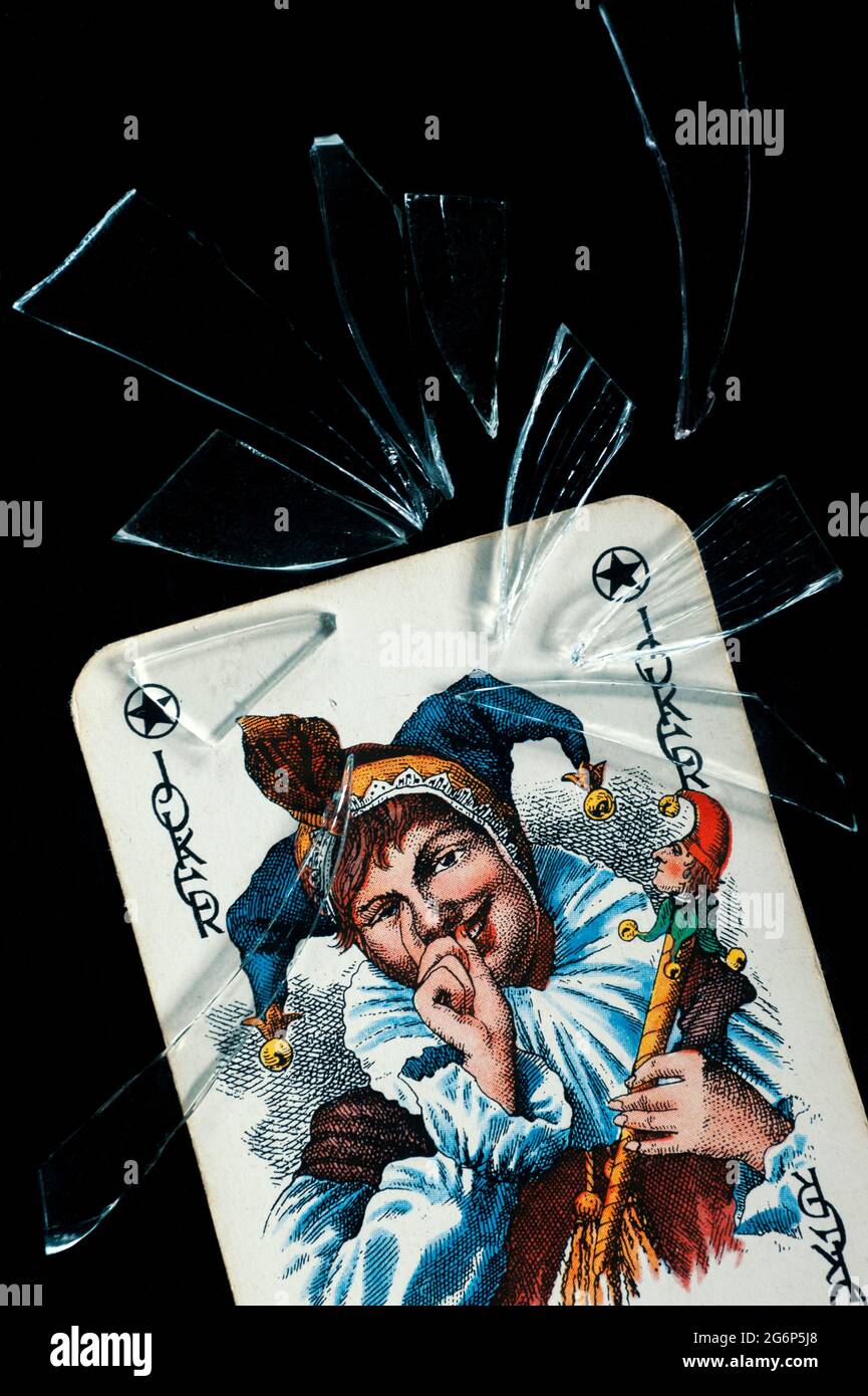 Joker playing card with glass shards against black background Stock Photo