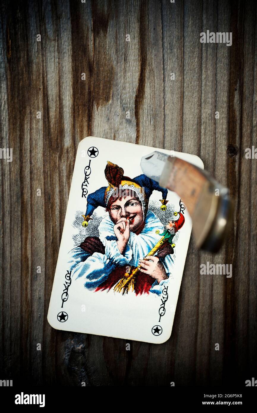 Joker playing card spiked on a wooden surface with a knife Stock Photo