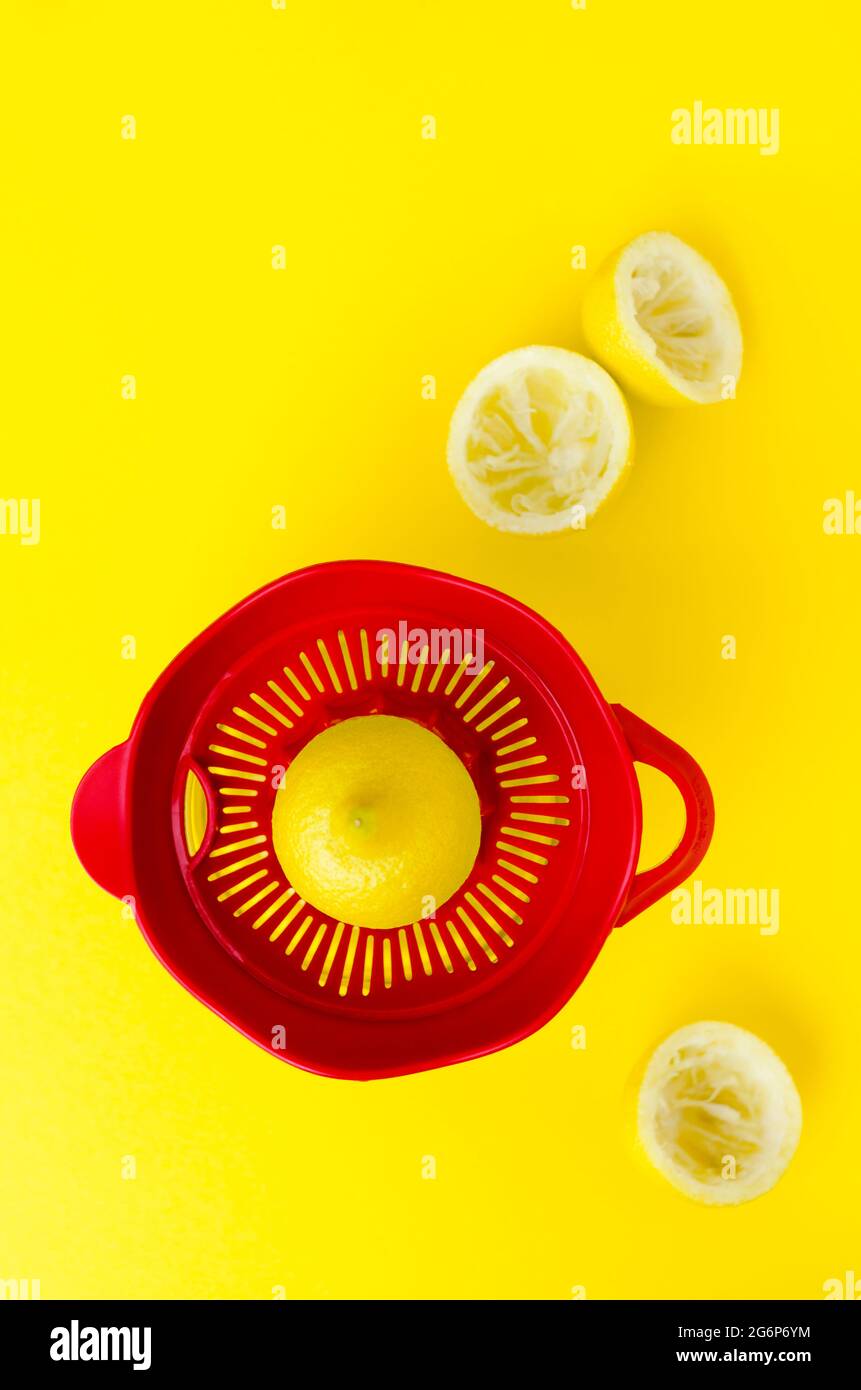 Red lemon squeezer with lemons on a yellow background Stock Photo