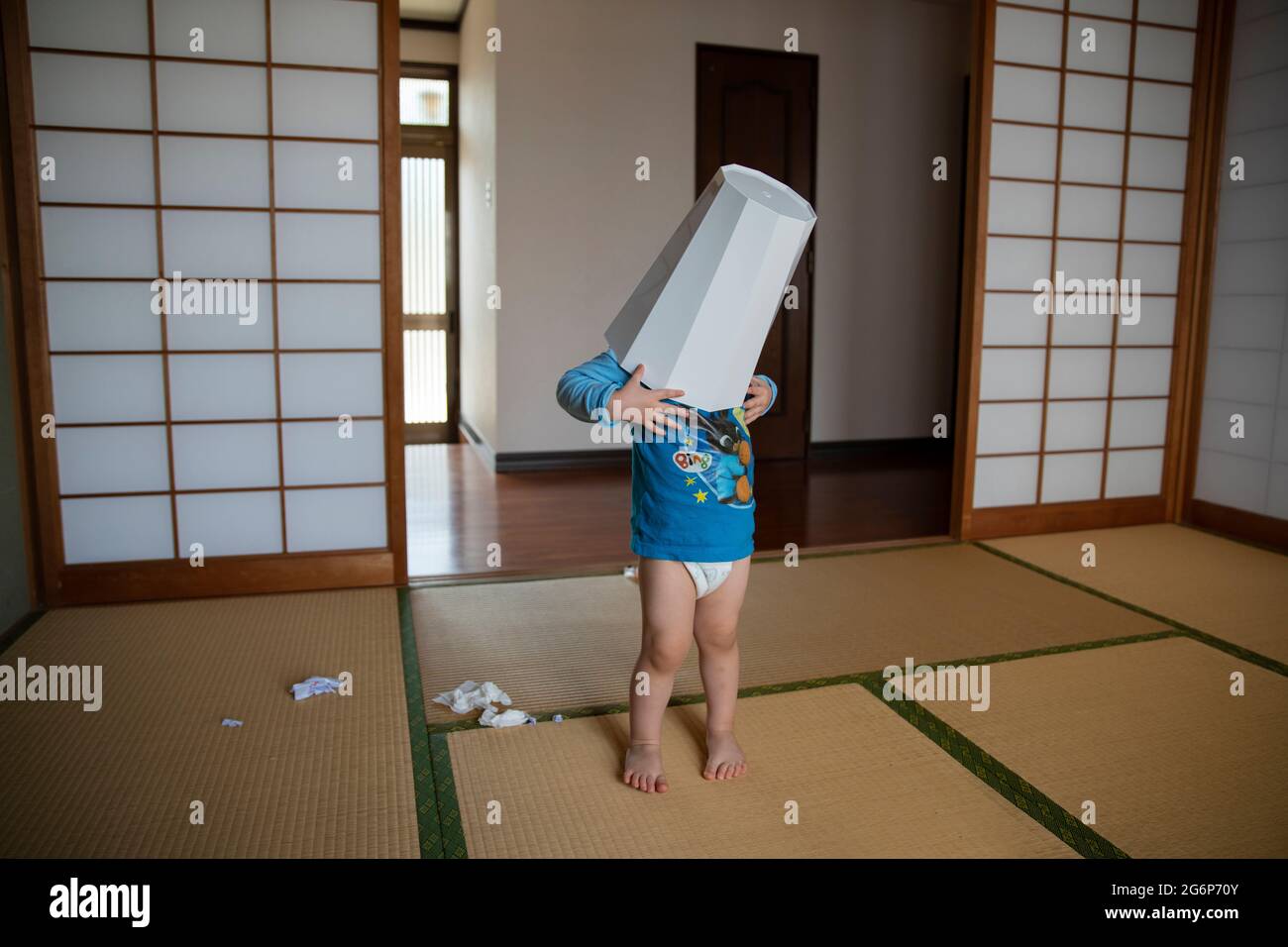 A young boy playing with a rubbish bin in a tatami room in Japan Stock Photo