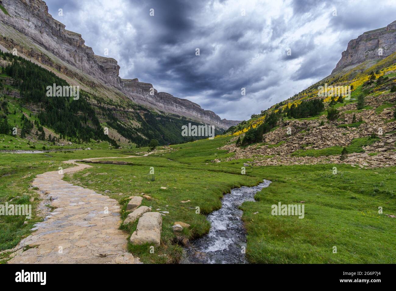 Hiking trail with small mountain creek under rain clouds in the spanish