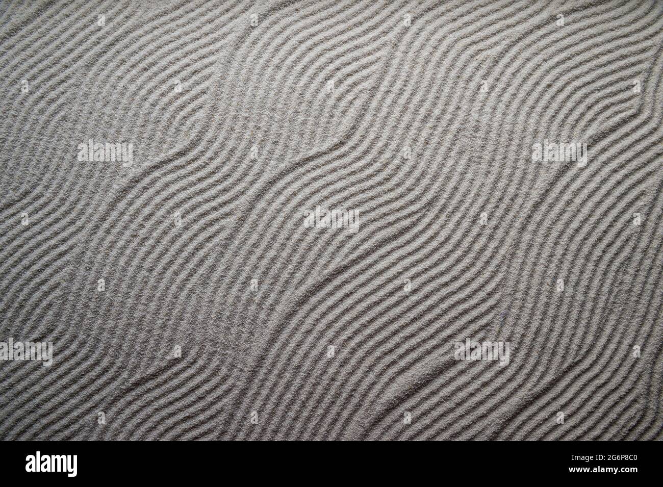 Simple graphic wave patterns raked into a background in the white gravel of a Japanese Zen garden Stock Photo