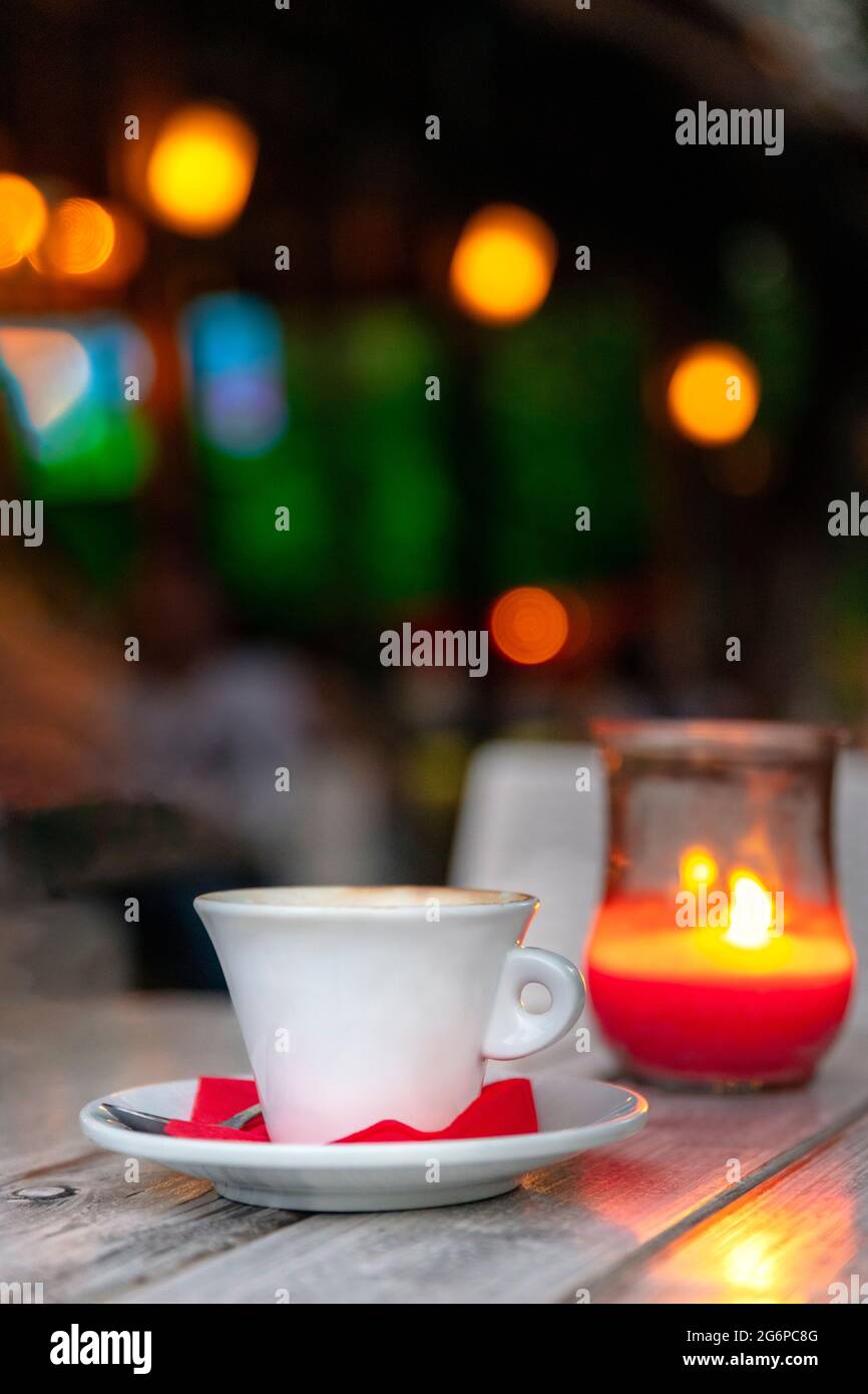 Cup of coffee on a wooden table at night by candle light, outdoors Stock Photo
