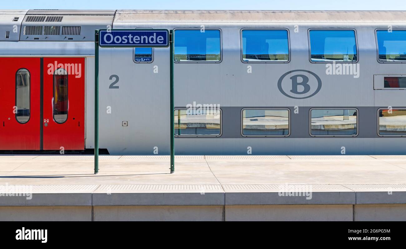 Train platform with double decker train with Oostende (Ostend) city train station name sign, Belgium. Stock Photo