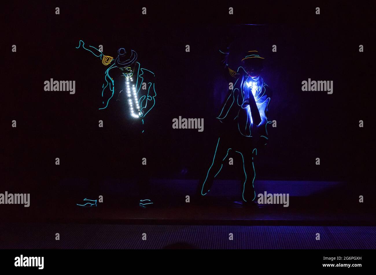 Dance team in LED costumes on a black background Stock Photo