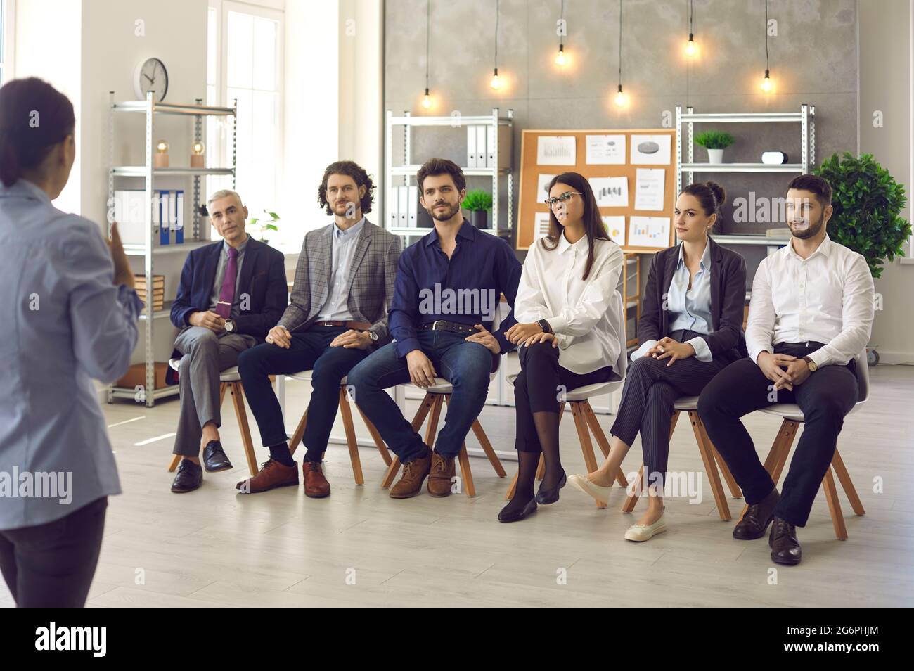Group of diverse employees who listen intently to their female colleague at a business meeting. Stock Photo