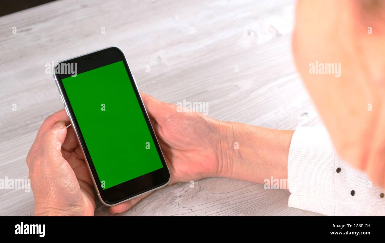 Middle-aged female senora uses an iPhone smartphone with a chroma key screen, copy space. Online shopping concept, use of mobile applications: Moscow Stock Photo
