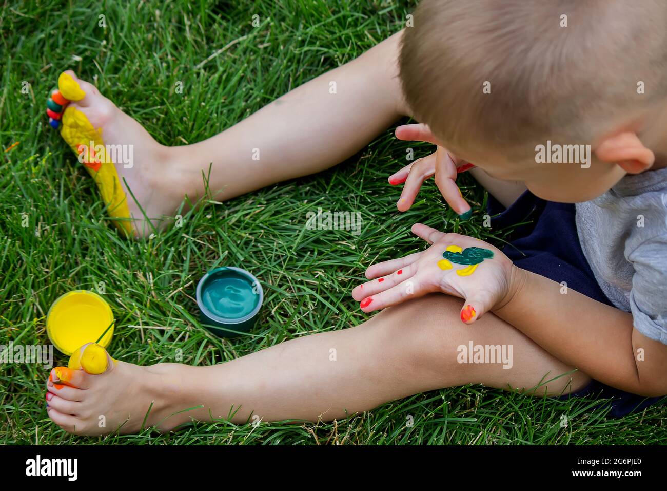 The child draws a pattern on the leg. A funny drawing with bright colors on the body. Selective focus Stock Photo