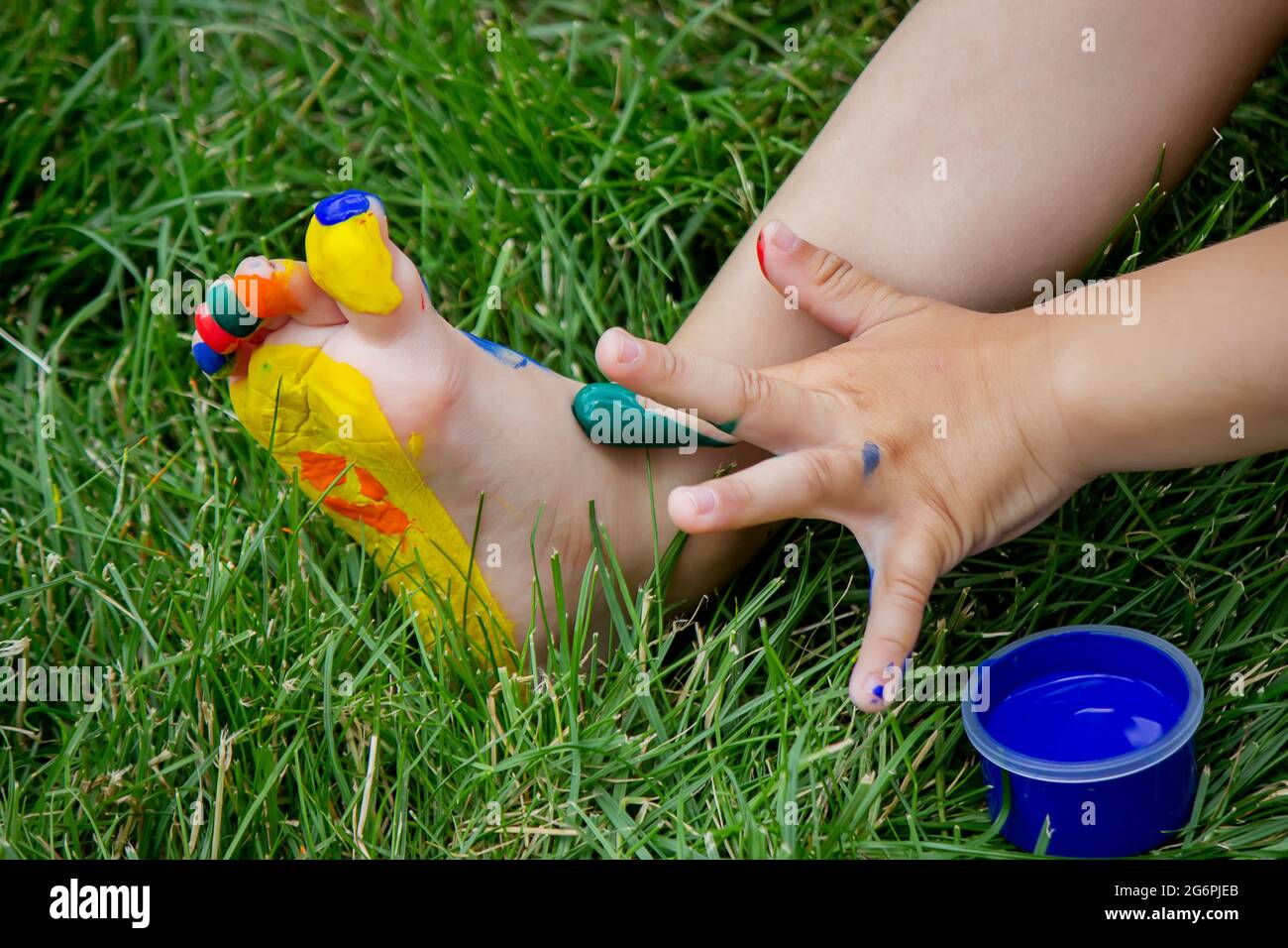 The child draws a pattern on the leg. A funny drawing with bright colors on the body. Selective focus Stock Photo