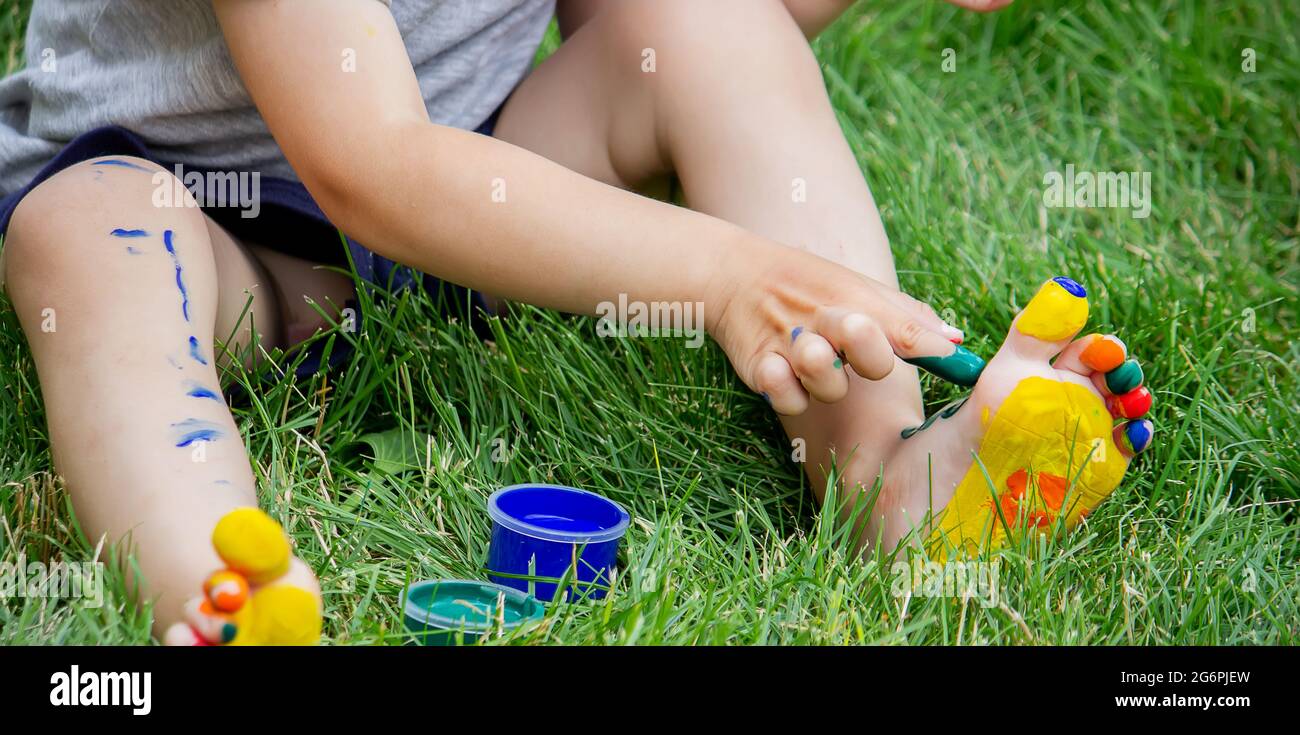 The child draws a pattern on the leg. A funny drawing with bright colors on the body. Selective focus Stock Photo