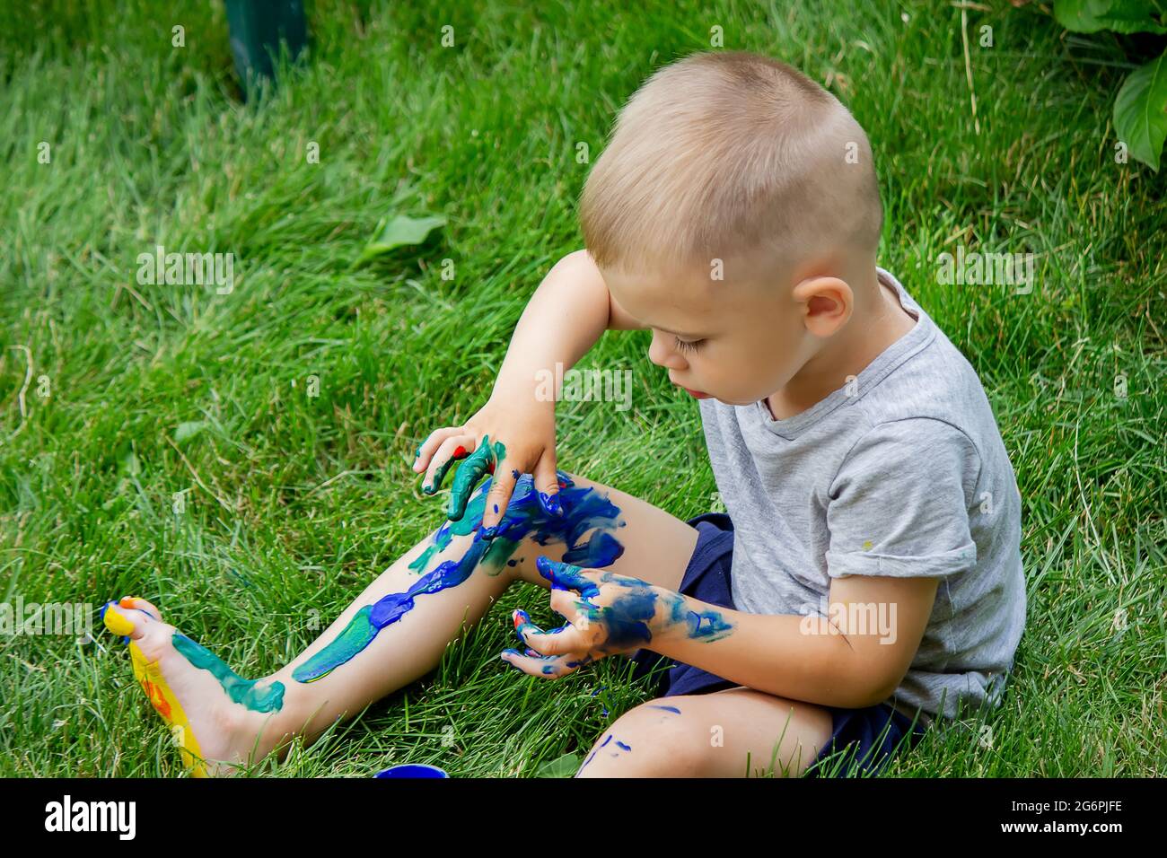 The child draws a pattern on the leg. A funny drawing with bright colors on the body. Selective focus Stock Photo