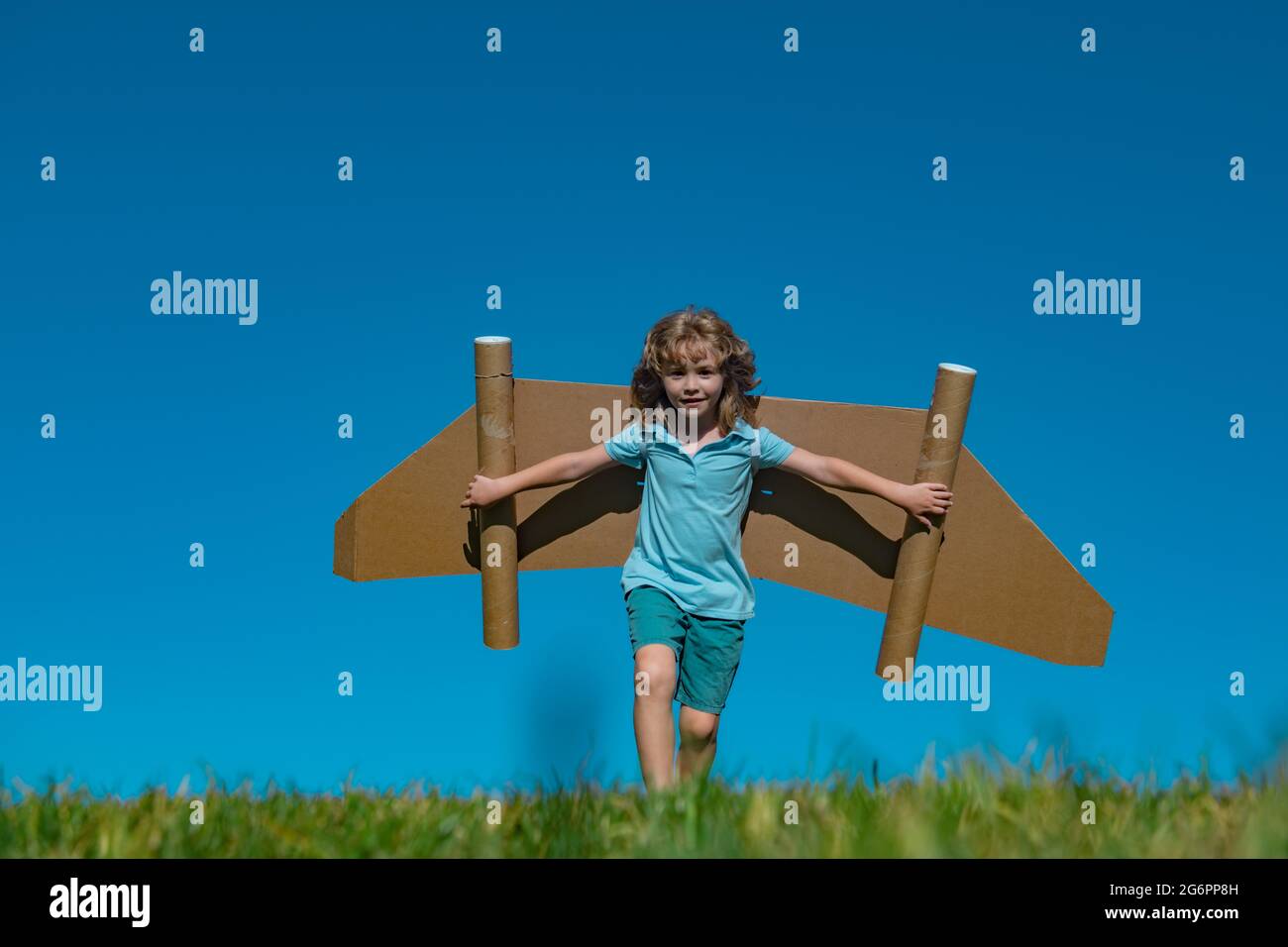 Happy child play with toy plane cardboard wings against blue sky. Kid ...