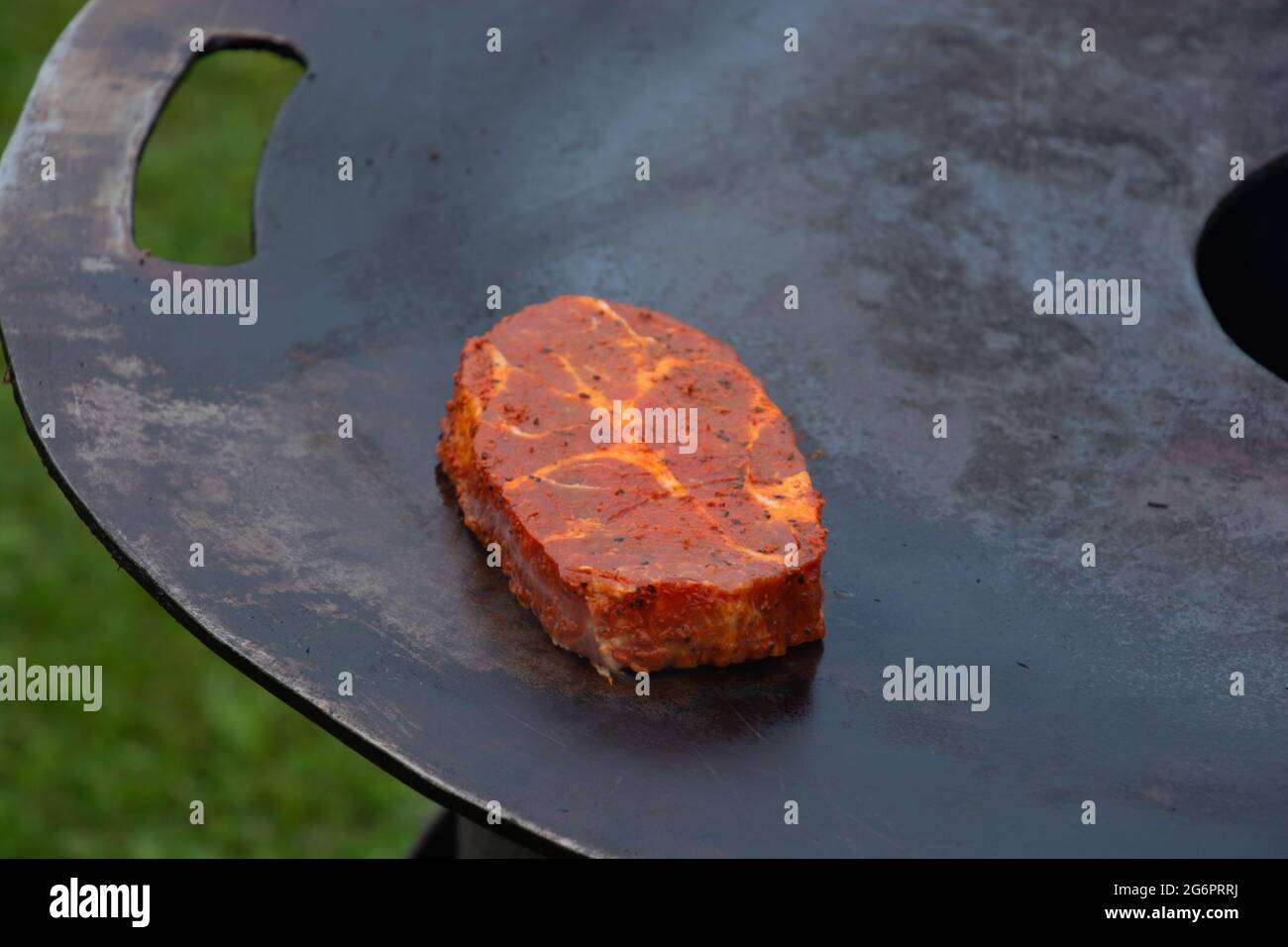 grill plate on hot wood fire with marinade pork steak close-up Stock Photo