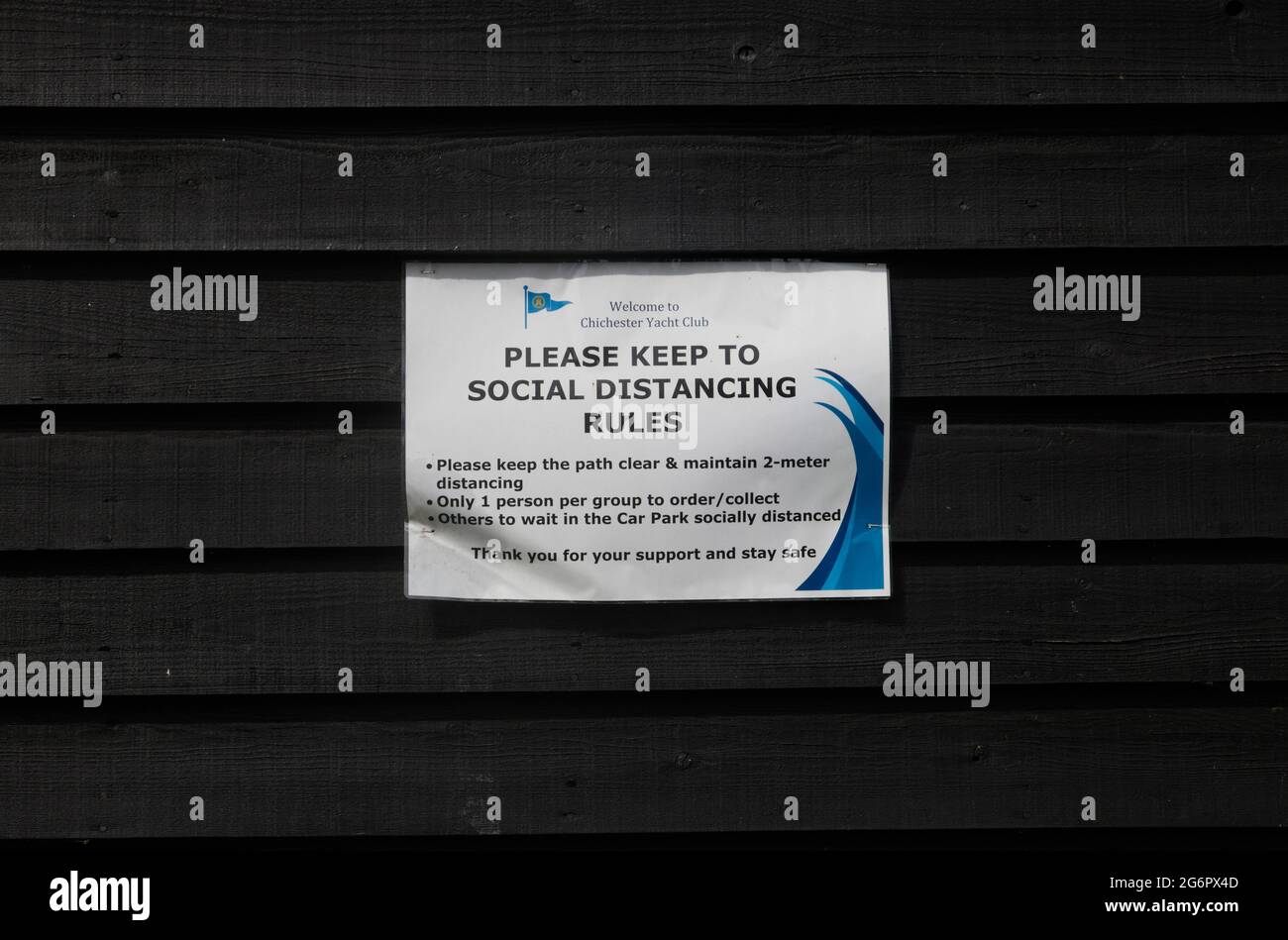 Notice of social distancing rules seen pinned on a wooden wall in the UK. Stock Photo