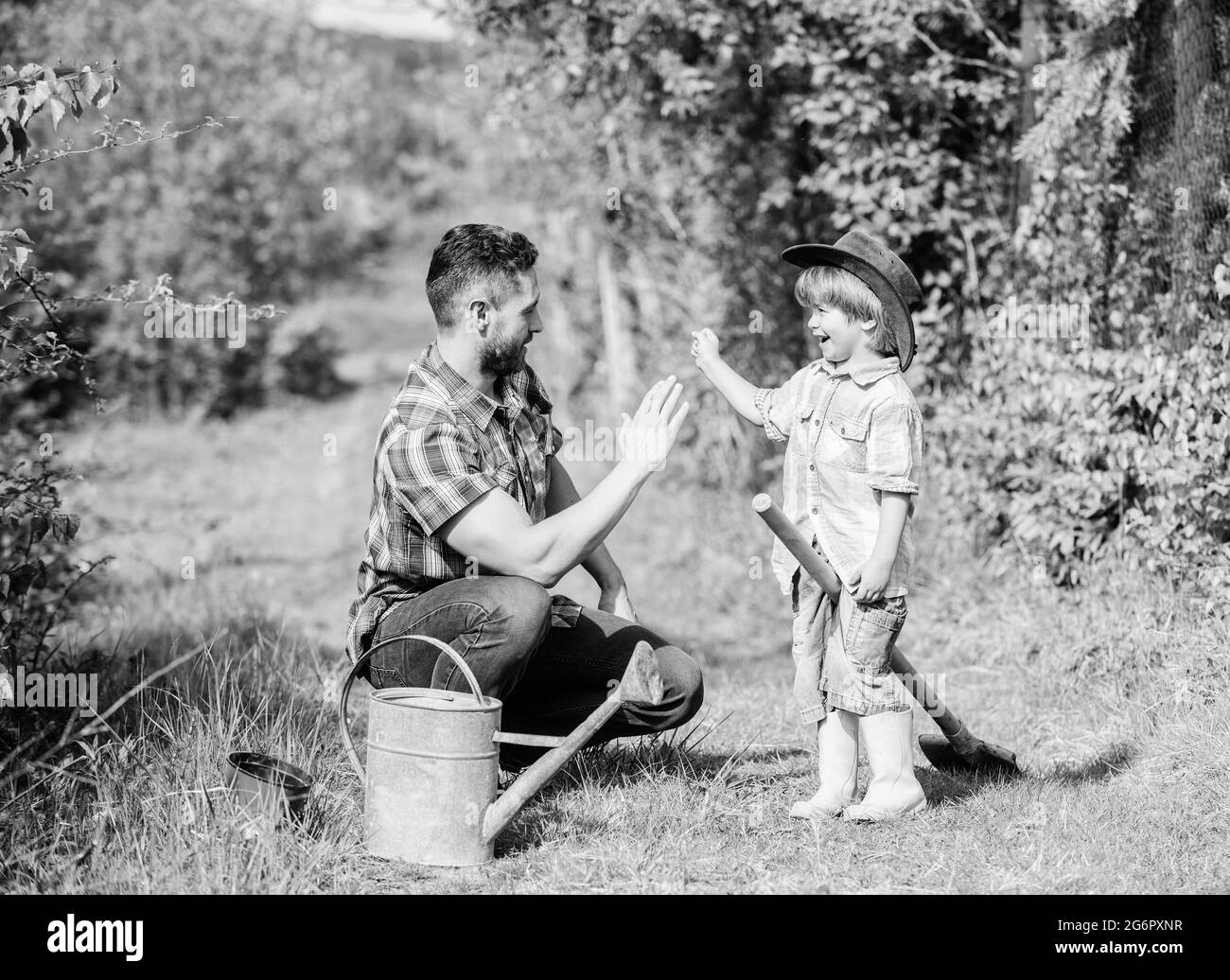 small boy child help father in farming. use watering can and pot. Garden equipment. Eco farm. father son in cowboy hat on ranch. happy earth day Stock Photo
