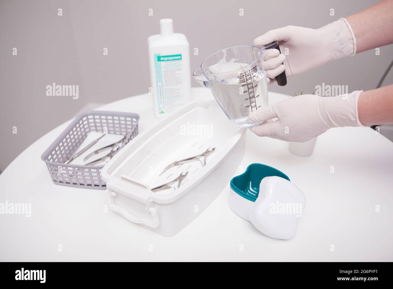 Manicurist pouring liquid sterilizer into container with nail nippers Stock Photo