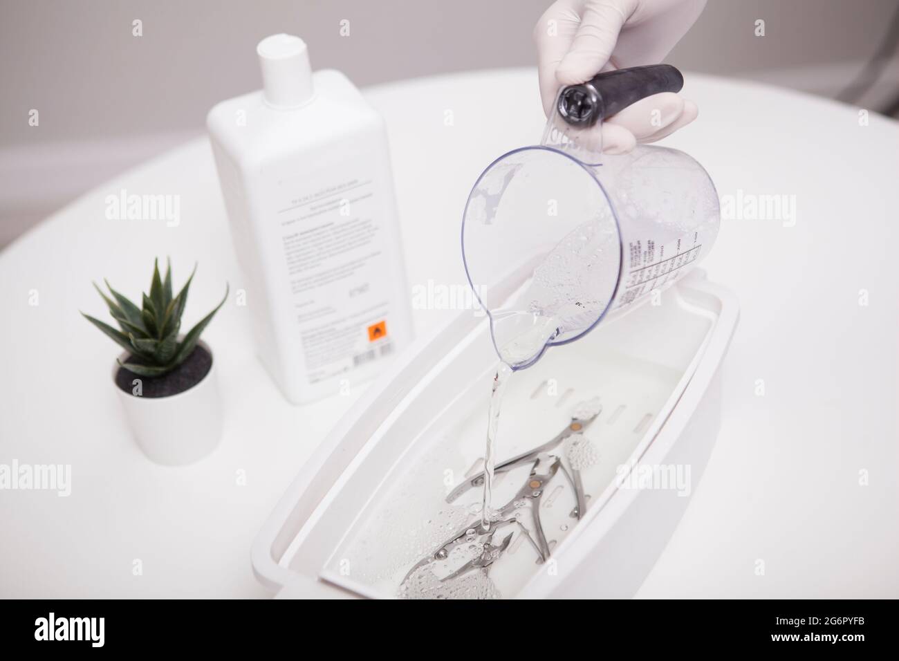 Close up of manicurist pouring liquid sterilizer into container with nail nippers Stock Photo