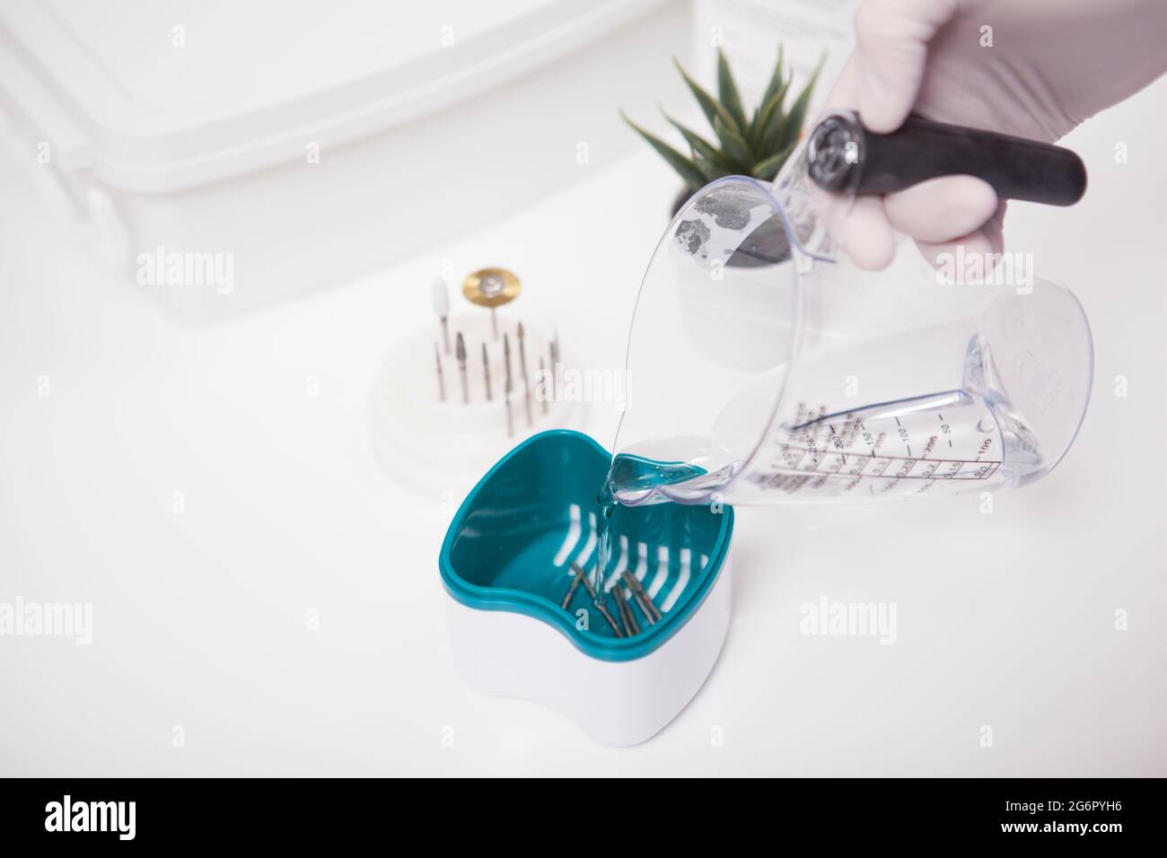 Close up of manicurist cleaning nail drill bits in liquid sterilizer Stock Photo