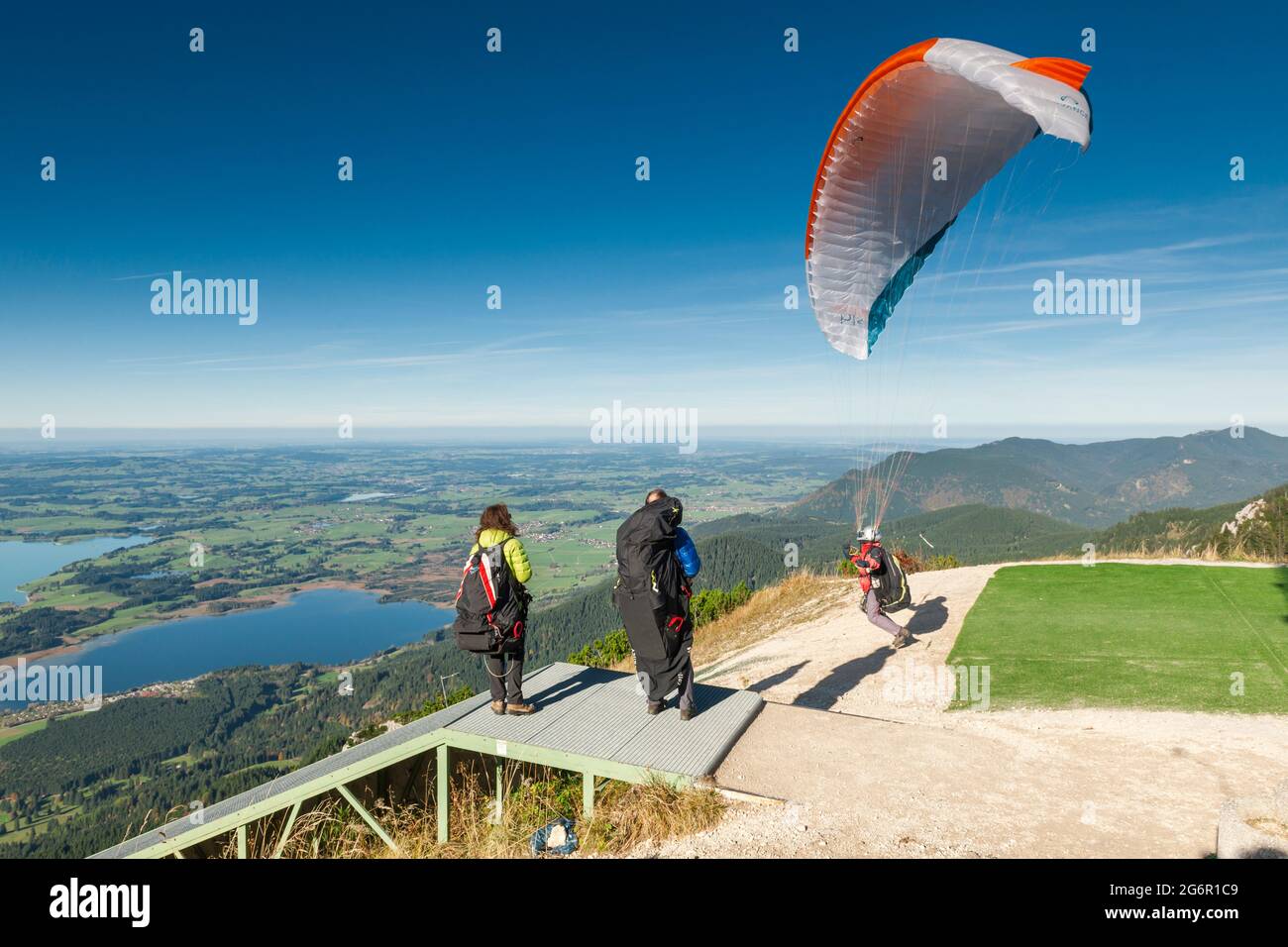 Schwangau, Germany - October 11, 2017: Paragliders starting on the Tegelberg at the jump point with other athletes standing next to them. Stock Photo