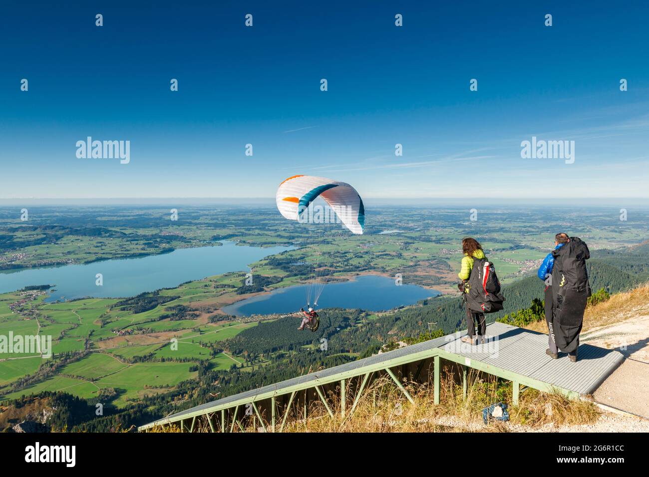 Schwangau, Germany - October 11, 2017: Paragliders starting on the Tegelberg at the jump point with other athletes standing next to them. Stock Photo