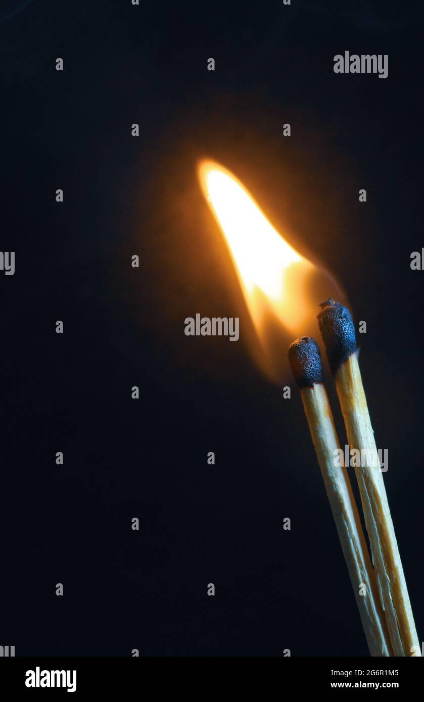 A couple of matches burning together with heat flame isolated on a black background Stock Photo