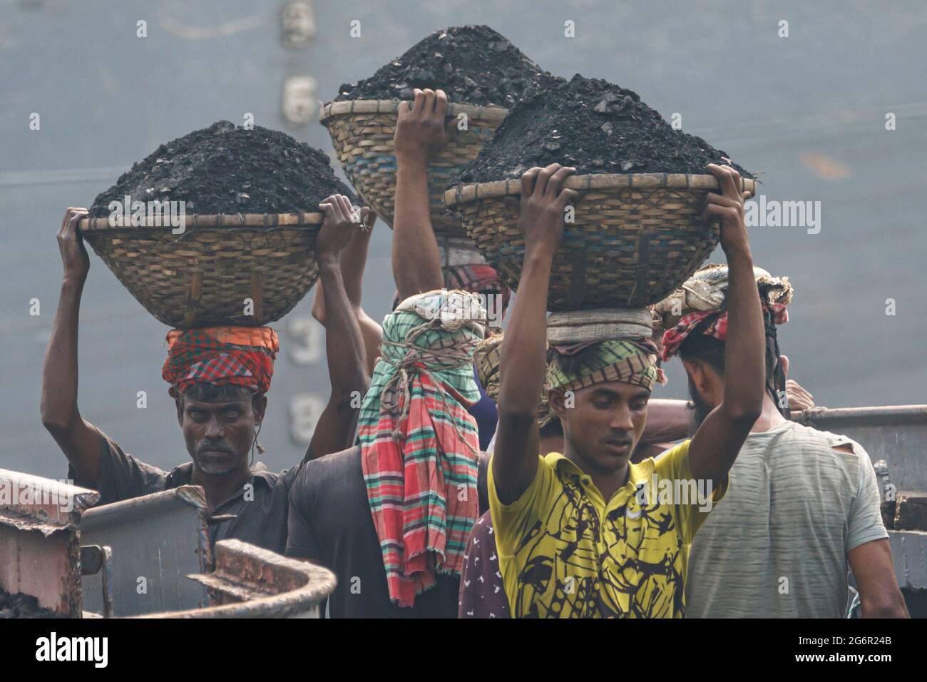 A human chain of porters carry coal, sand and gravel from the barges ...