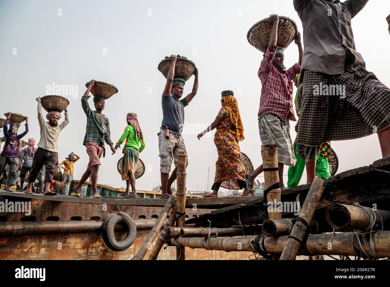 A human chain of porters carry coal, sand and gravel from the barges ...