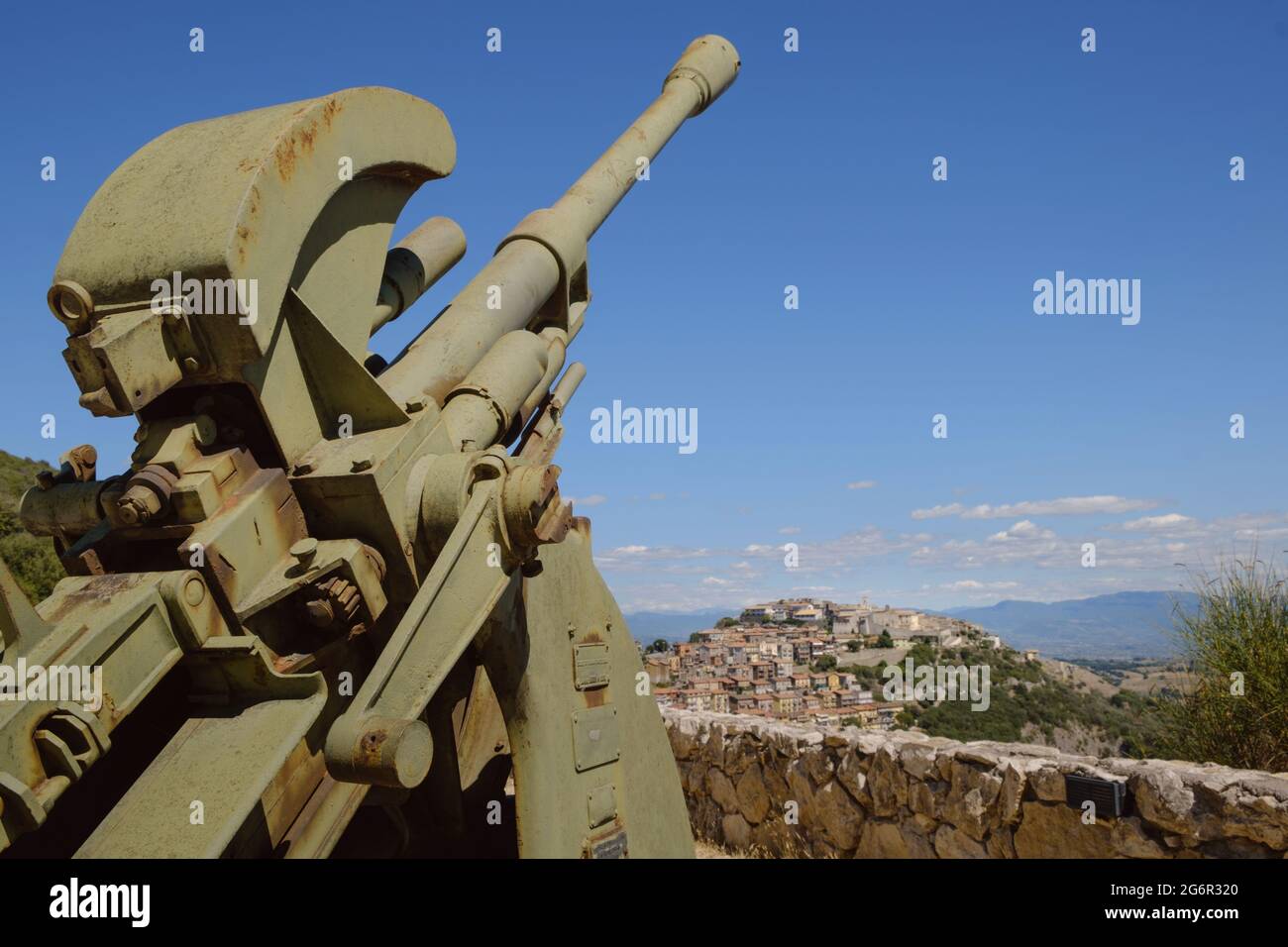 Ancient Sant' Oreste hamlet on the background with a ww2 anti aircraft cannon in foreground near Monte Soratte shelter, Sant'Oreste, Rome, Italy Stock Photo