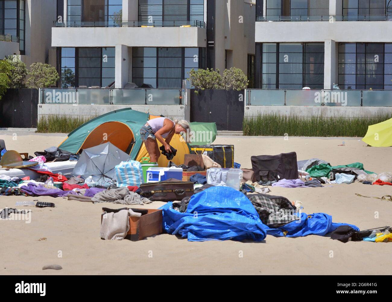 Los Angeles, United States. 08th July, 2021. A homeless woman sorts through her belongings at Venice Beach in Los Angeles on Wednesday, July 7, 2021. Fliers posted by the city outlined a five-week 'phased resumption of normal operations' with a 'comprehensive beachfront cleaning' of the area, which is under the jurisdiction of the city Recreation and Parks Department. The warning said the 'unhoused residents currently living in the park will be offered housing.' Photo by Jim Ruymen/UPI Credit: UPI/Alamy Live News Stock Photo
