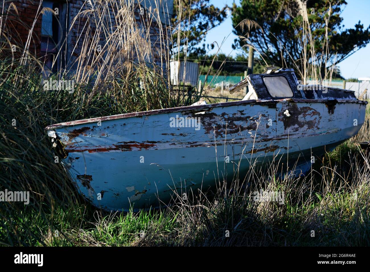An old boat has been left high and dry, deserted by a coastal inlet Stock Photo