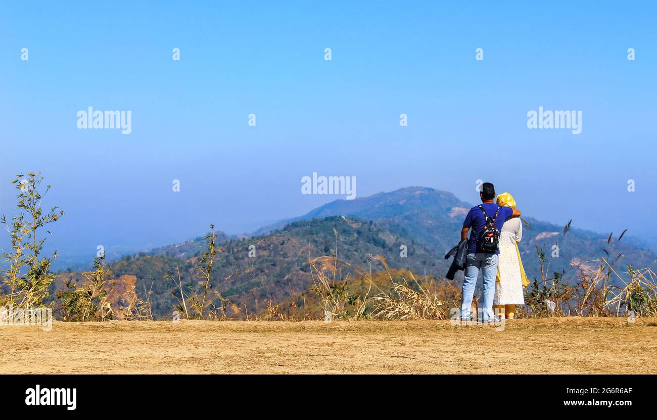 Man and woman standing and hugging on the top of the mountain, autumn hike with backpacks. Nilgiri Hill, Bandarban, Bangladesh. Stock Photo