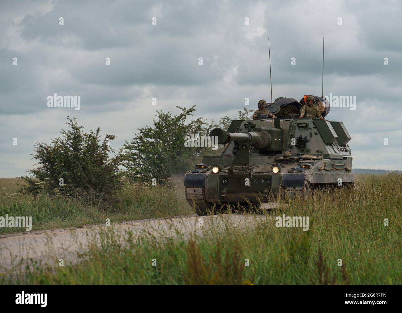 british army military AS-90 (Gun Equipment 155mm L131) armoured self-propelled howitzer gun hurtling along a stone track creating clouds of dust in a Stock Photo
