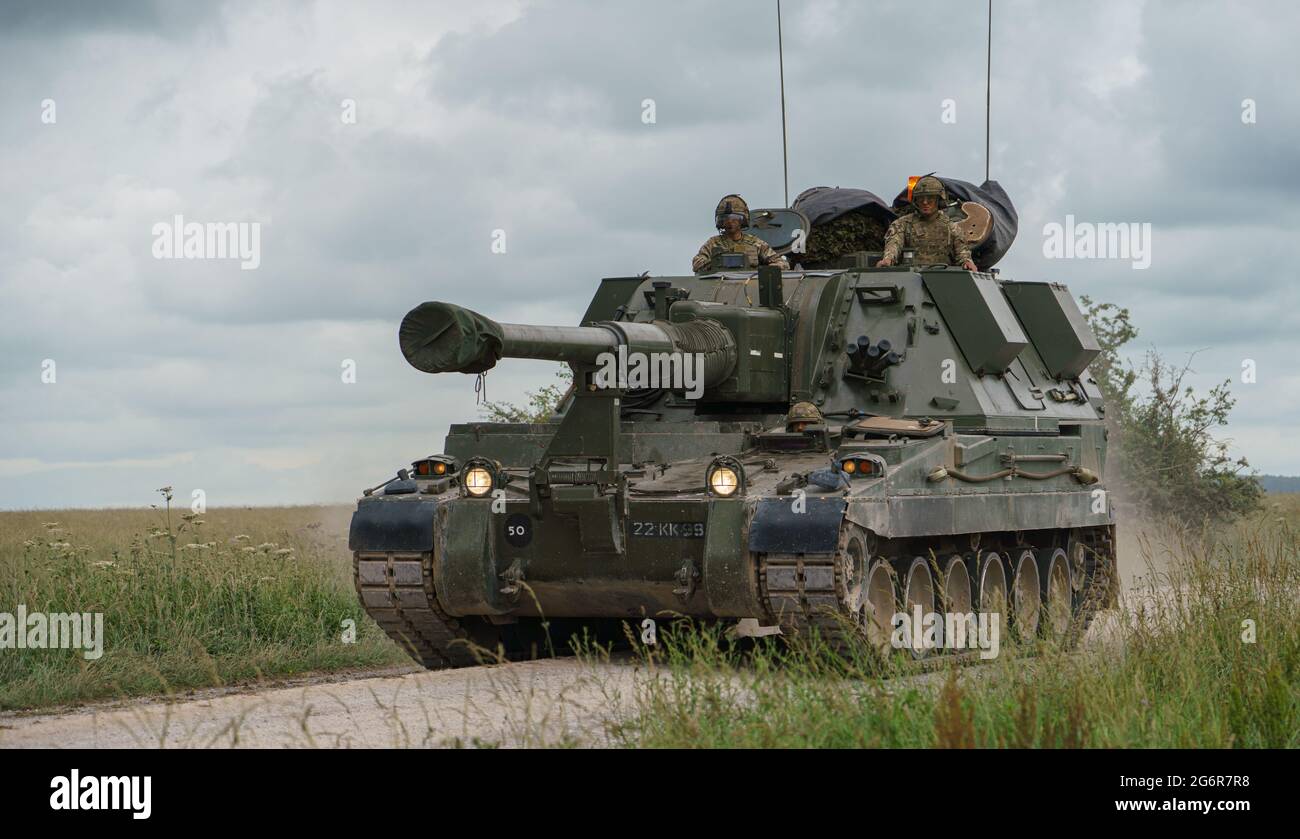british army military AS-90 (Gun Equipment 155mm L131) armoured self-propelled howitzer gun hurtling along a stone track creating clouds of dust in a Stock Photo