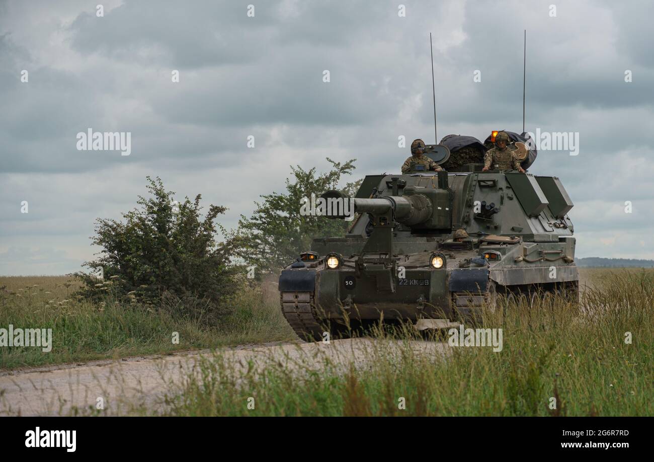 british army military AS-90 (Gun Equipment 155mm L131) armoured self-propelled howitzer gun hurtling along a stone track creating clouds of dust in a Stock Photo