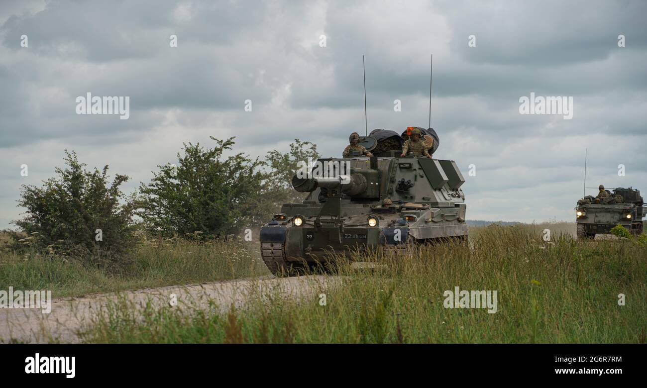 british army military AS-90 (Gun Equipment 155mm L131) armoured self-propelled howitzer gun hurtling along a stone track creating clouds of dust in a Stock Photo
