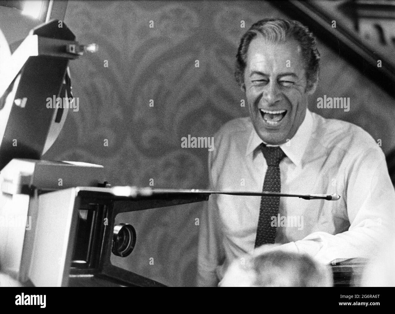 REX HARRISON as Henry Higgins on set candid with Movie Camera during filming of MY FAIR LADY 1964 director GEORGE CUKOR from the Broadway musical adapted from the play Pygmalion by George Bernard Shaw screenplay book and lyrics Alan Jay Lerner  music Frederick Loewe production design and costumes Cecil Beaton producer Jack L.Warner Warner Bros. Stock Photo