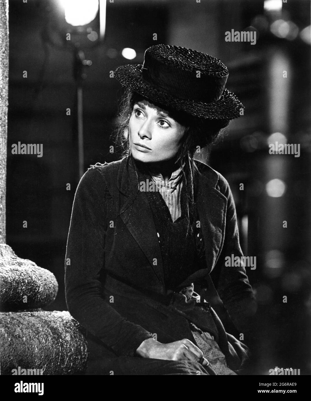 AUDREY HEPBURN on set candid portrait in costume as Eliza Doolittle for Covent Garden scenes during filming of MY FAIR LADY 1964 director GEORGE CUKOR from the Broadway musical adapted from the play Pygmalion by George Bernard Shaw screenplay book and lyrics Alan Jay Lerner  music Frederick Loewe production design and costumes Cecil Beaton producer Jack L.Warner Warner Bros. Stock Photo