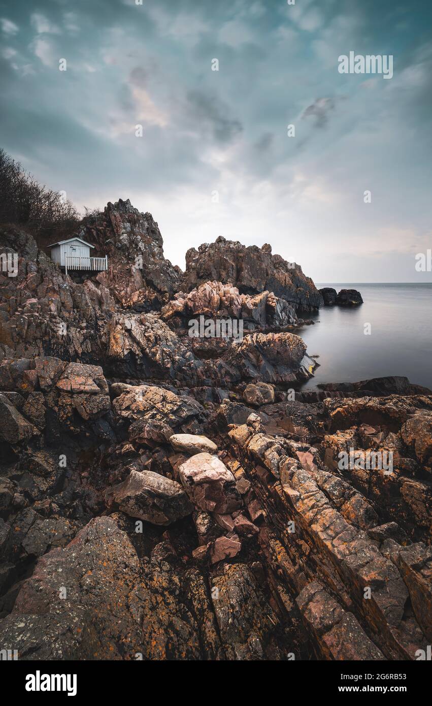 Dramatic cliff coastal landscape with small cottage on the edge. Arild, Sweden. Stock Photo