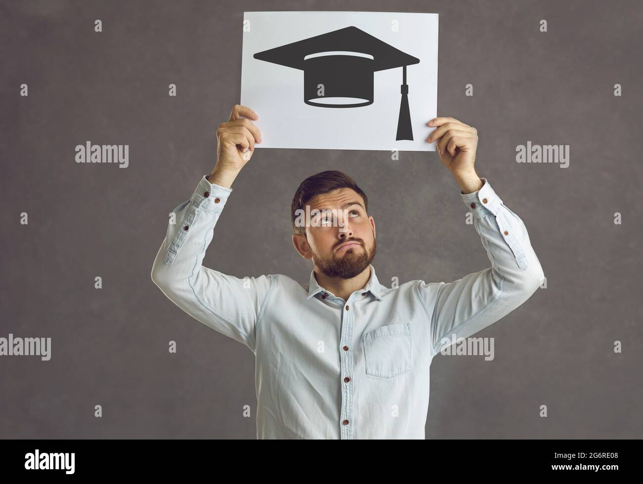 Student with a picture of an academic cap thinking of getting a university degree Stock Photo