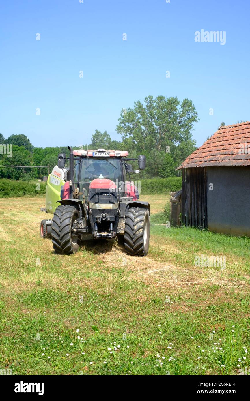 case 170 cvx tractor with claas 465 rc baler behind in rural meadow baling dried cut grass into bales zala county hungary Stock Photo