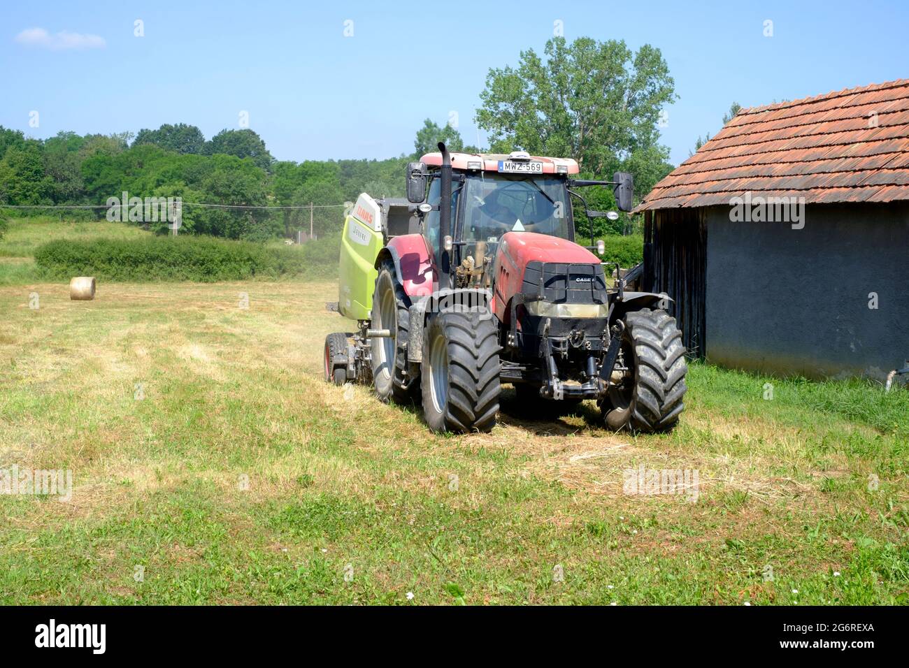 case 170 cvx tractor with claas 465 rc baler behind in rural meadow baling dried cut grass into bales zala county hungary Stock Photo