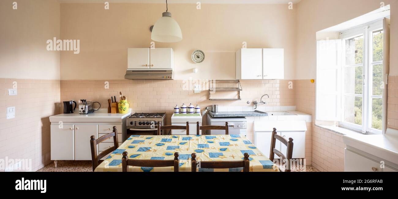 Interior of an old kitchen, almost antique, a table in the middle, the space is large and it is also bright. There is no style, they are pieces of fur Stock Photo